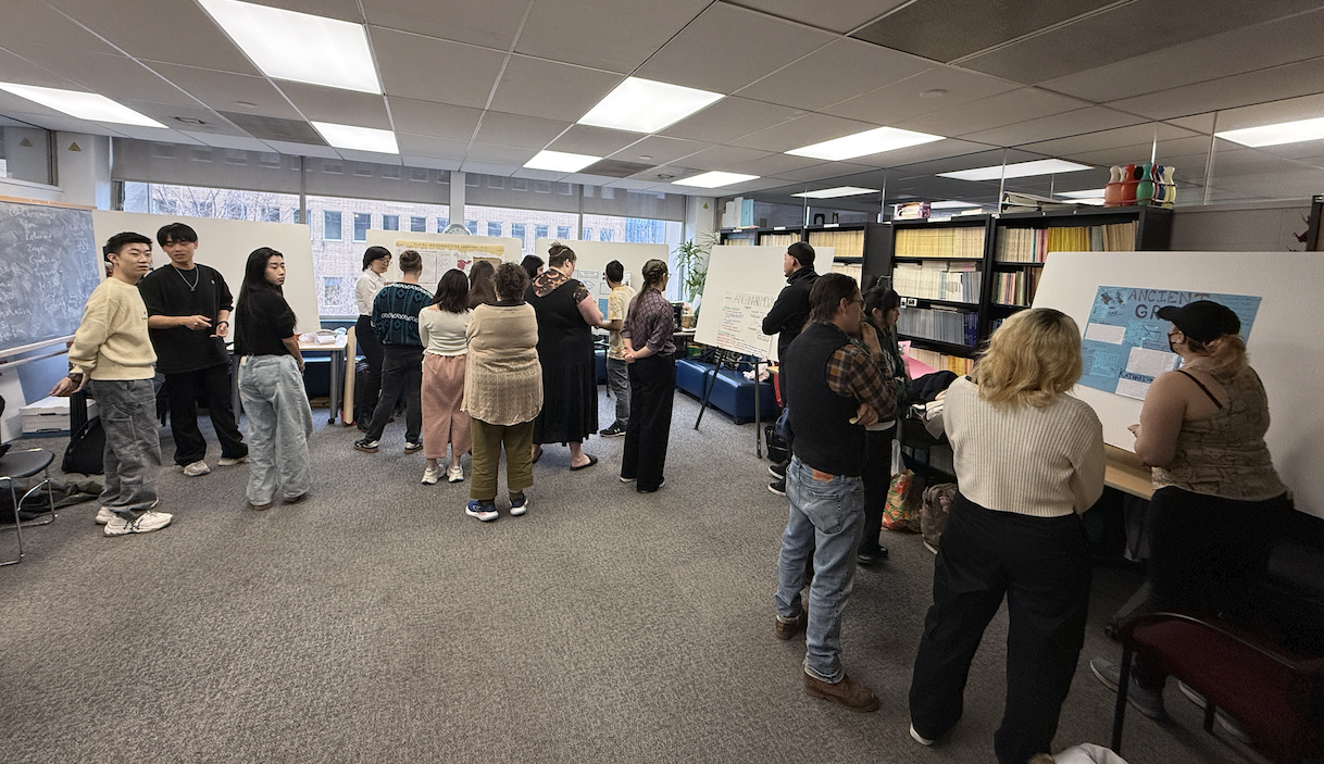 picture of LIN458 students gathered in the linguistics lounge looking at posters during the poster session