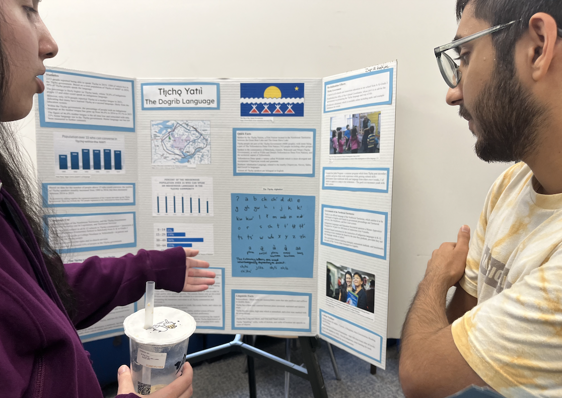 two students gathered around a poster on language revitalization, in the linguistics lounge.