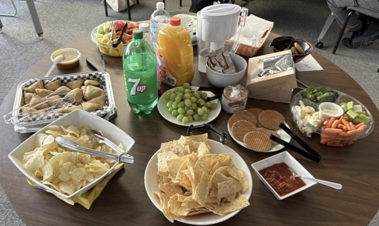 a table in the linguistics lounge with food and soda and plates